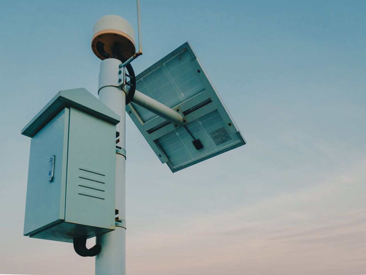 Home A solar panel paired with a security camera against a clear sky, representing renewable technology.